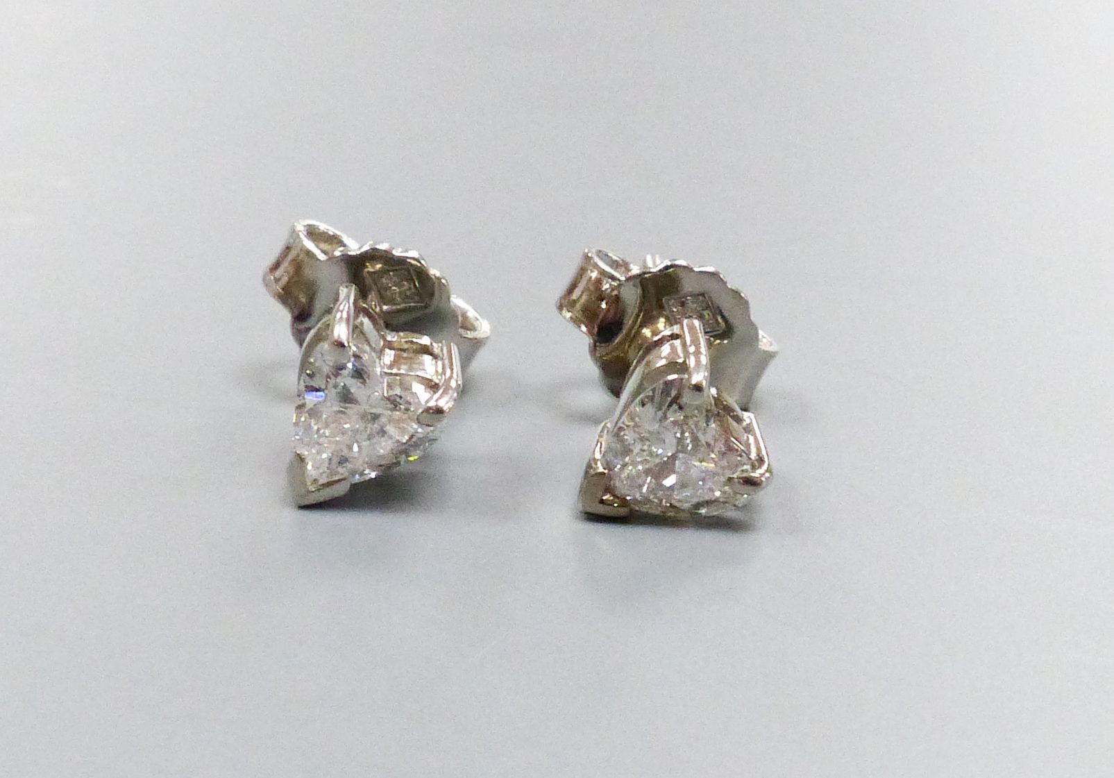 A pair of modern white metal and solitaire heart shaped diamond set ear studs, diameter approx. 5mm, gross weight 3.2 grams.